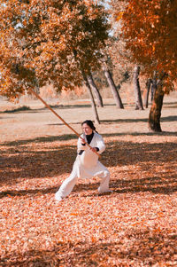 Woman practicing martial arts on autumn leaves