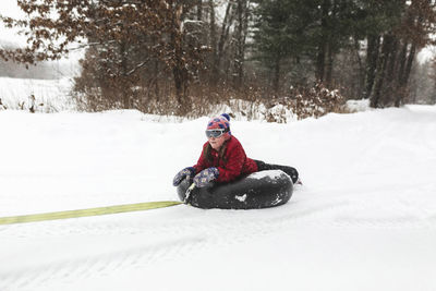 Girl lying on inflatable ring in forest during winter