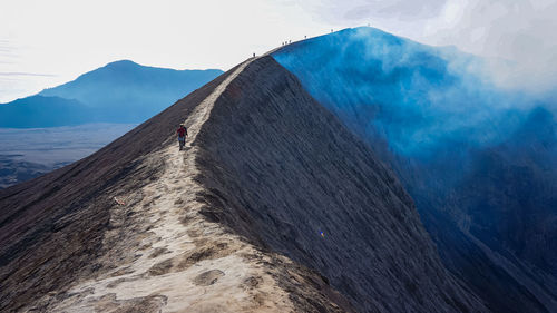 People hiking on mountain against sky