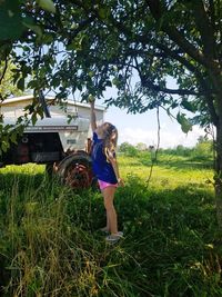 Full length of woman standing on grass against trees