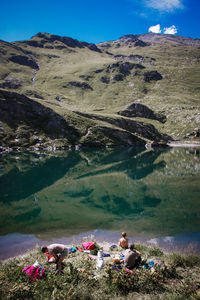 People on mountain by lake against sky