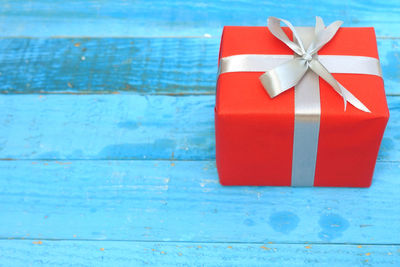 Close-up of red wrapped gift box on blue table