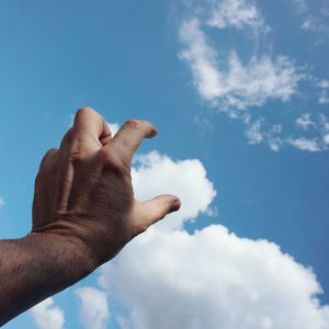 Hand touching the clouds in the blue sky