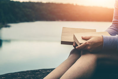 Midsection of man holding paper while sitting by sea