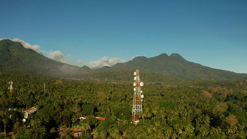 Telecommunication tower, communication antenna against mountains and rainforest, aerial view. 