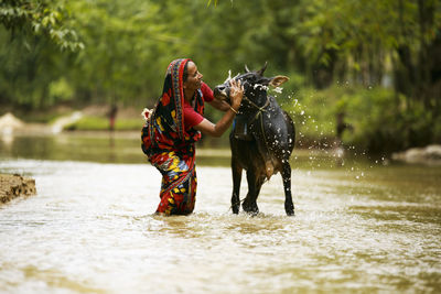 Side view of woman with dog running in lake