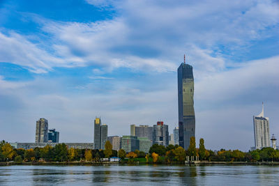 River by modern buildings against sky in city