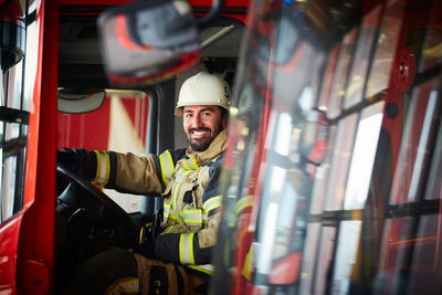 Portrait of mid adult firefighter sitting in fire truck at fire station