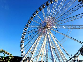 Low angle view of ferris wheel against clear blue sky