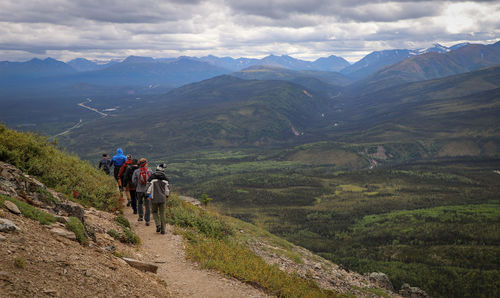 Rear view of people riding motorcycle on mountain road