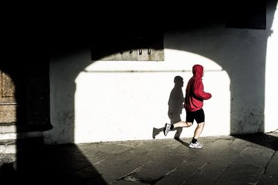 Full length side view of man jogging against white wall