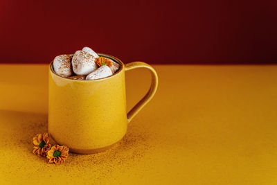 Still life of a yellow mug of hot cocoa with marshmallows.