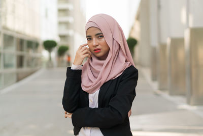 Portrait of businesswoman wearing hijab while standing against buildings