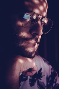 Sunlight falling on thoughtful man wearing eyeglasses in darkroom