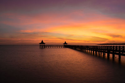Silhouette pier over sea against sky during sunset