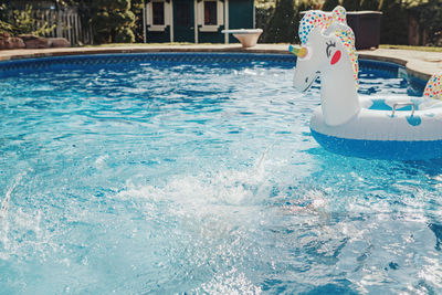 Water drops in blue water in swimming pool. inflatable swimming large toy unicorn floating in water