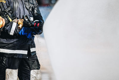 Midsection of firefighter holding hose