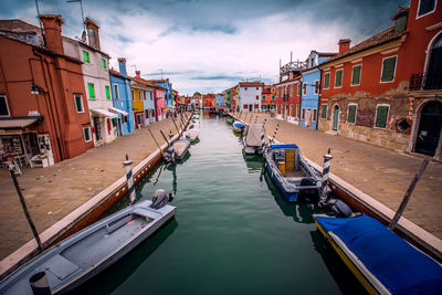 Boats moored in canal amidst buildings in city