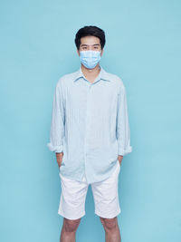 Portrait of young man standing against blue background