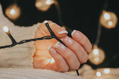 Midsection of woman holding illuminated string lights