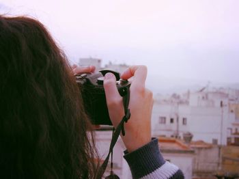 Close-up of cropped woman holding camera