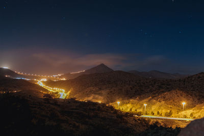 Panoramic view of illuminated mountains against sky at night