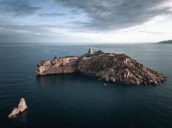 Rock formation in sea against sky