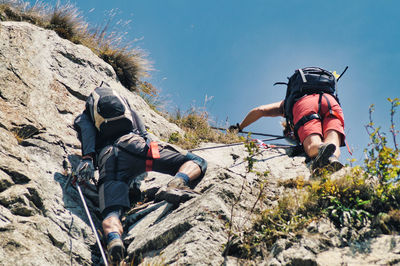 Low angle view of friends climbing on rock formation