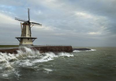 Stormy weather near a windmill in vlissingen straight on the north sea.