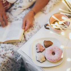 Woman lying on bed having breakfast on holidays. christmas cookies and and donut.  wishes new year