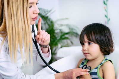 Female doctor examining while gesturing girl in hospital