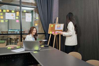 Midsection of woman using digital tablet while sitting in office