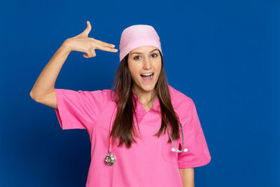 Portrait of smiling young woman standing against blue background