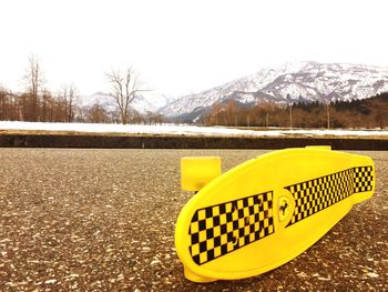 Close-up of yellow arrow sign on snow covered landscape