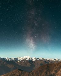 Scenic view of snowcapped mountains against star field