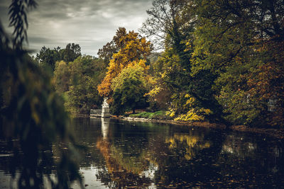Trees by lake against sky during autumn