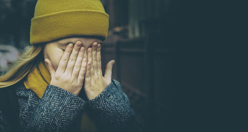 Close-up of girl with hands covering eyes in home