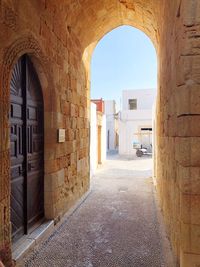 Road amidst buildings against sky seen through arch door