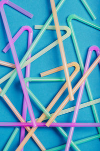 Directly above shot of multi colored drinking straw over blue background