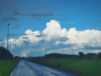 Empty road amidst field against sky