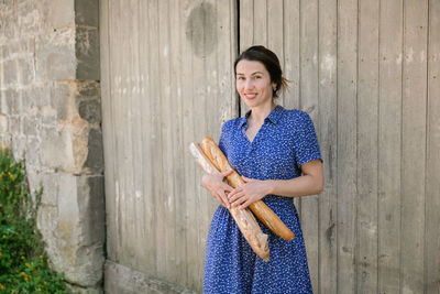Young woman standing with french baguettes in the countryside
