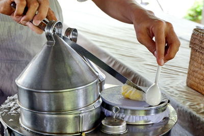 Close-up of hand pouring water in container