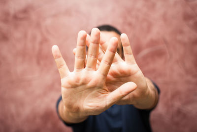 Man gesturing stop while standing against wall