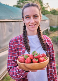 Portrait of smiling young woman holding food on table