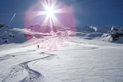 People skiing on snowcapped mountain against sky on sunny day