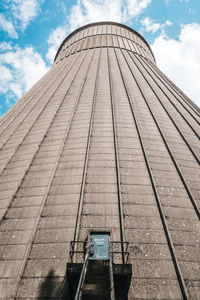 Low angle view of cooling tower against cloudy sky