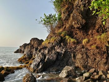 Rock formation by sea against clear sky