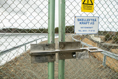 Text on chainlink fence against sky