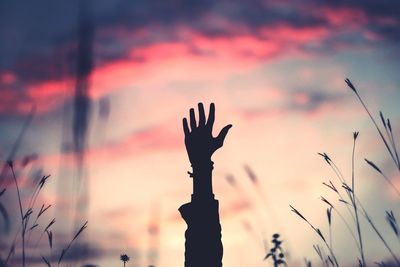 Silhouette hand against sky during sunset