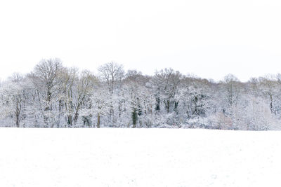 Snow covered field against clear sky